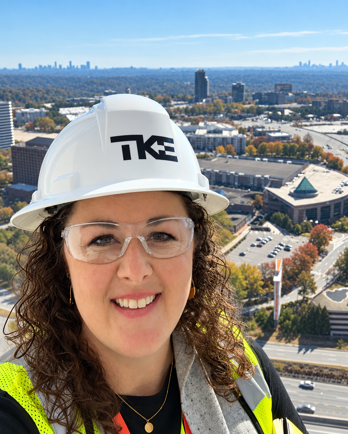 Monica Miller Brown in a TK Elevator hard hat and safety glasses above the Atlanta skyline