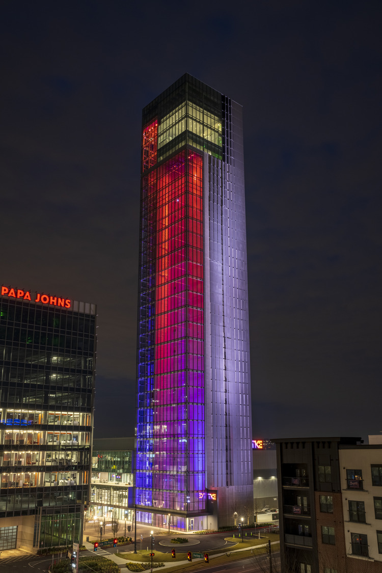 The IQC test tower lit at night, its transparent skin showing the machinery inside